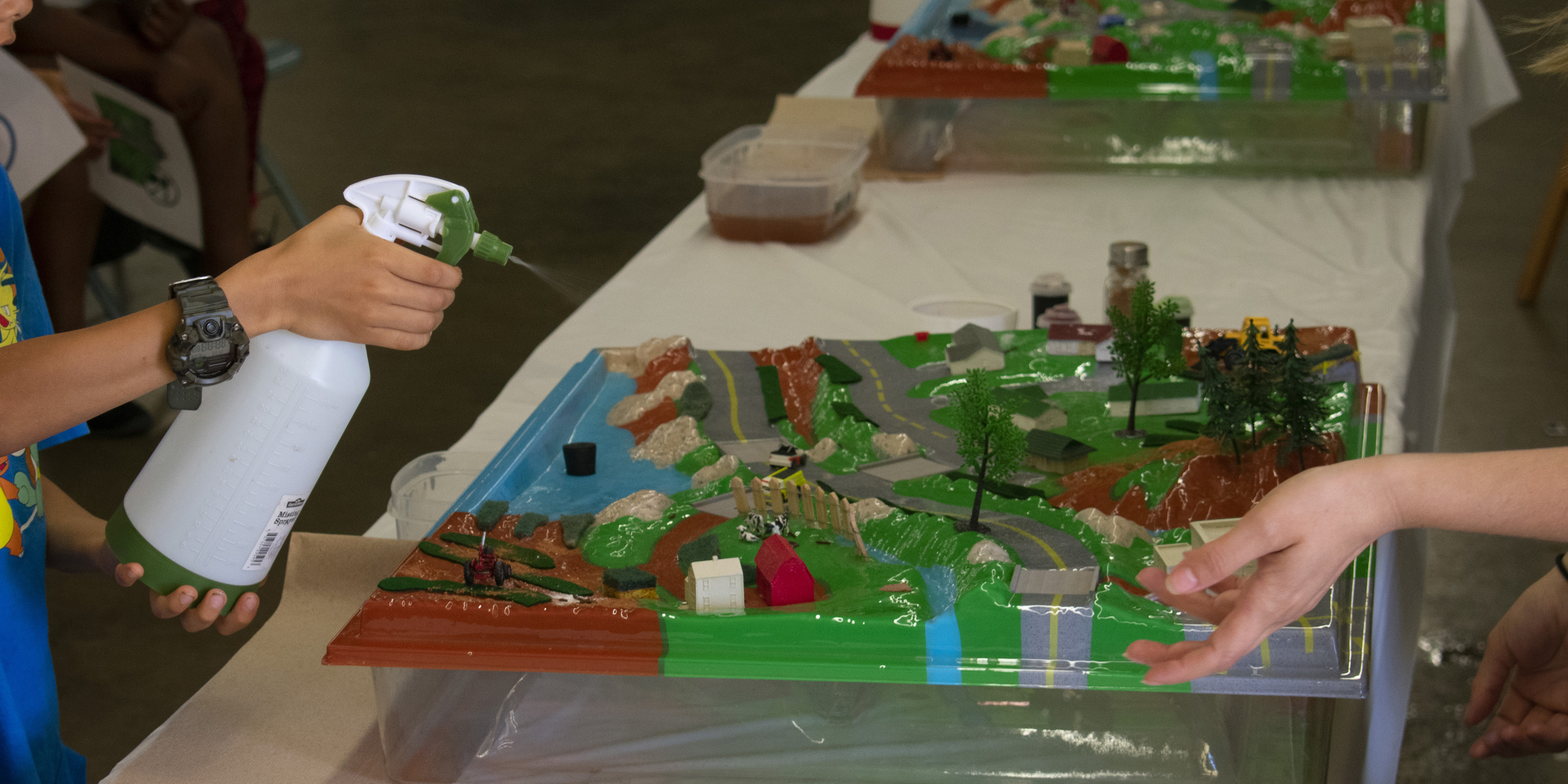 A child simulates rain to examine pollutant runoff into Maryland watersheds